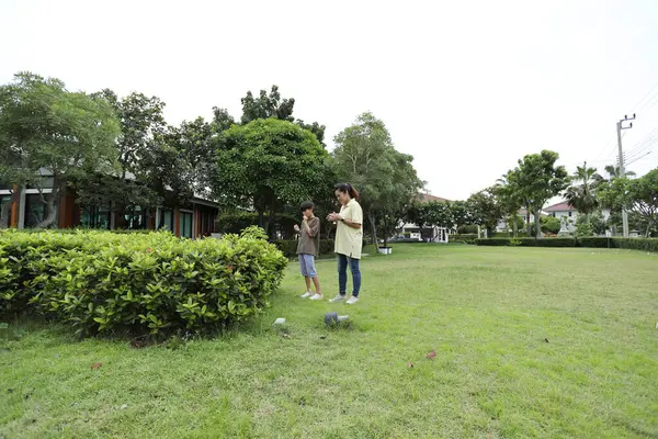 Güneydoğu Asya 'lı bekar bir anne çocuğuyla parkta vakit geçirir ve bitki, böcek ve doğal çevre gibi doğa temelli öğrenme faaliyetleriyle ilgilenir..