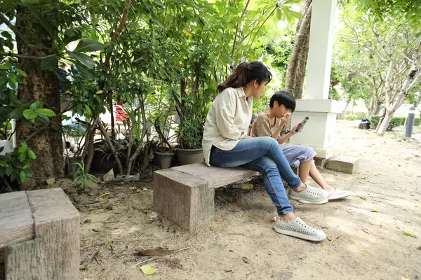 Güneydoğu Asya 'lı bekar bir anne çocuğuyla parkta vakit geçirir ve bitki, böcek ve doğal çevre gibi doğa temelli öğrenme faaliyetleriyle ilgilenir..