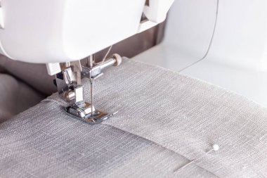 Modern sewing machine presser foot with linen fabric and thread, closeup, copy space. Sewing process clothes, curtains, upholstery. Business, hobby, handmade, zero waste, recycling, repair concept