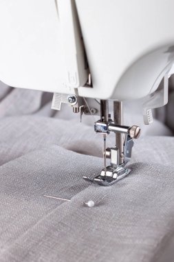 Modern sewing machine presser foot with linen fabric and thread, closeup, copy space. Sewing process clothes, curtains, upholstery. Business, hobby, handmade, zero waste, recycling, repair concept