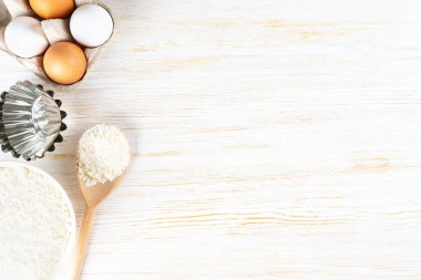 Baking cooking Ingredients background with copy space. Flour, eggs, milk, bakeware on white wooden surface. Top view, flat lay. Mockup menu, banner, header for site, baking concept