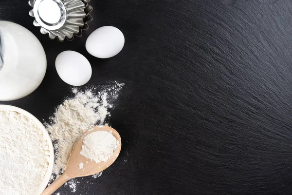 stock image Baking cooking Ingredients background with copy space. Flour, eggs, milk, bakeware on black slate surface. Top view, flat lay. Mockup menu, banner, header for site, baking concept