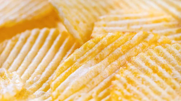 stock image Yellow crispy ridged potato chips close up. Food background, banner, header, wallpaper.