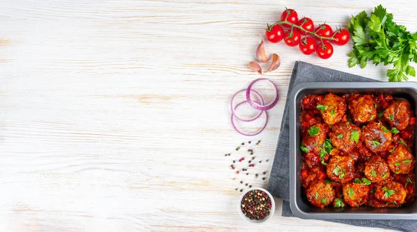 Homemade meatballs with tomato sauce and spices served in black pan on white background. Tasty cooked meat balls made with minced beef and food ingredients. Top View, Flat lay, banner with copy space