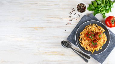 Homemade spaghetti with tomato sauce meatballs and spices served on white background. Tasty cooked pasta and meat balls made with minced beef, food ingredients. Top View, Flat lay, banner, copy space