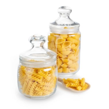 Fusilli ve Conchiglioni cam kavanozda, beyaz arka planda izole edilmiş. Cam kavanozlarda iki çeşit çiğ makarna, aşçı malzemesi, geleneksel İtalyan mutfağı..
