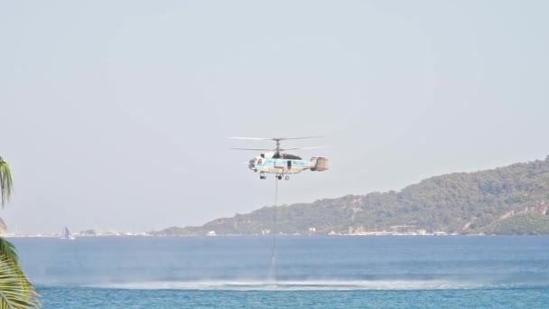 消防救助ヘリコプターは海の水のバケツを拾う 水バケツを再充填し 森林火災を消火するために海を離陸するプロセス — ストック動画