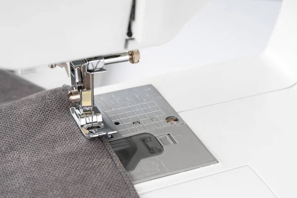 グレーの生地と糸で現代のミシンプレス足 クローズアップ 縫製プロセス服 カーテン ビジネス 手作り 廃棄物ゼロ リサイクル 修理の概念 — ストック写真
