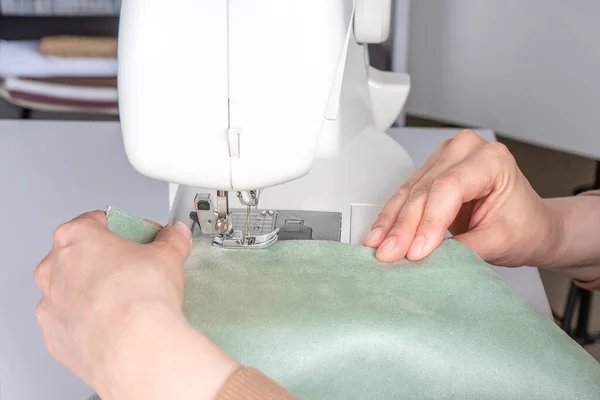 在工作室的现代缝纫机上 女性的手在缝制白色面料 妇女的手在缝纫机上缝制面料 业余爱好 小企业概念 — 图库照片