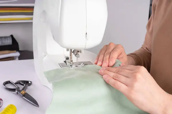 在工作室的现代缝纫机上 女性的手在缝制白色面料 女人的手在缝纫机上缝制面料 业余爱好 小企业概念 — 图库照片