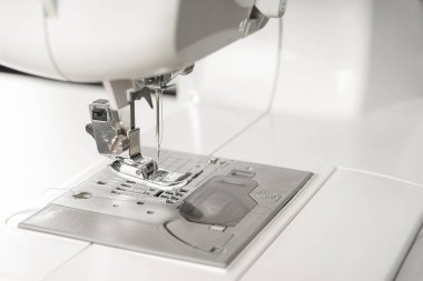 Modern beyaz dikiş makinesi presör ayak yakın çekim, makro. Dikiş ekipmanları, atölye işi, imalat, meslek için çalışma aracı.