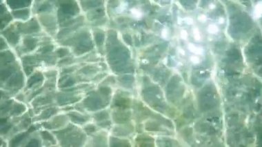 Pool water ripples and the reflection of the sun. Waves, movement of azure sea, ocean water with rays of the sun. Water abstract background. High quality FullHD footage