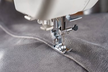 Gri kadife kumaşlı modern dikiş makinesi. Giysileri dikmek, perdeleri örmek. İş, hobi, el yapımı, sıfır atık, geri dönüşüm, tamir konsepti