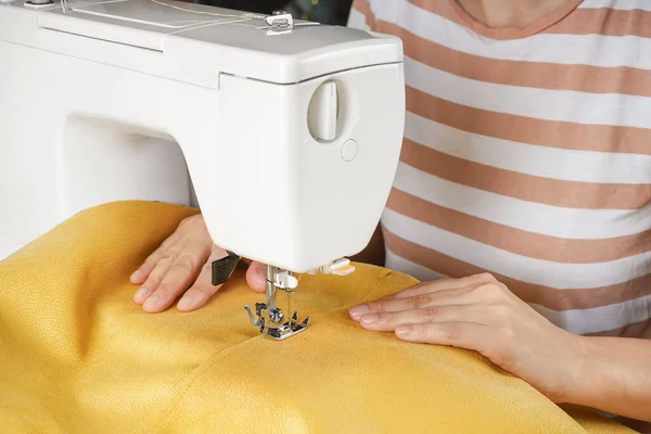 アトリエの職場でモダンなミシンにイエローファブリックをステッチするテーラーハンド 女性の手は縫製機のクローズアップに布の部分を縫います ハンドメイド 中小企業コンセプト — ストック写真