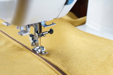 Sarı kadife kumaşlı modern dikiş makinesi. Özel basın mensubu ayak ve fermuarı kapat. Giysileri dikmek, perdeleri örmek. İş, hobi, el yapımı, sıfır atık, tamir konsepti