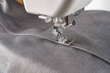 Gri kadife kumaşlı modern dikiş makinesi. Giysileri dikmek, perdeleri örmek. İş, hobi, el yapımı, sıfır atık, geri dönüşüm, tamir konsepti