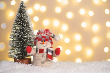 Oyuncak kardan adam ve kar üzerinde dekoratif Noel ağacı ve parlayan ışıklar arka planda. Noel, yeni yıl tebrik kartı ve fotokopi alanı. Tatil aydınlatması, ev dekorasyonu.
