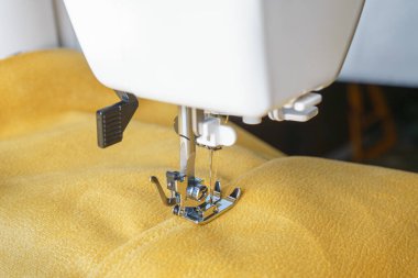 Sarı kadife kumaşlı modern dikiş makinesi. Özel basın mensubu ayak ve fermuarı kapat. Giysileri dikmek, perdeleri örmek. İş, hobi, el yapımı, sıfır atık, tamir konsepti