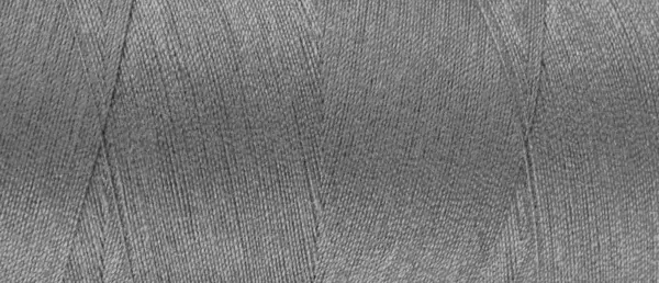 Texture of gray color threads in spool close up, macro. Wide banner, header of sewing threads bobbin abstract background, wallpaper, backdrop.