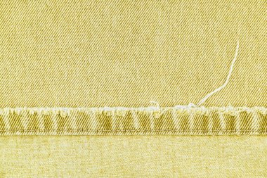 Sarı kot pantolon pantolon paçavrası, kot kumaş arka planda, yakın plan, makro. Yırtık kotlar dikilmiş, yırtılmış. Duvar kağıdı, arkaplan, tasarım ayrıntıları.