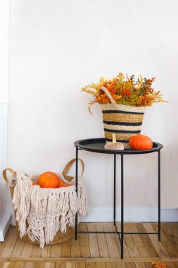 Sonbahar süslemeleri, içinde mevsimlik yapraklar ve küçük turuncu balkabağı ve sepet bulunan dokuma sepetli siyah masa ev içinde dekoratif balkabakları içerir. Cadılar Bayramı, Şükran Günü Dekorasyonu