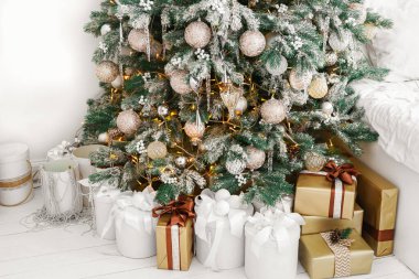 Güzel dekore edilmiş Noel ağacının altında beyaz ve altın süslemelerle paketlenmiş tatil hediyeleri. Kış tatilinin neşeli atmosferi. Duvar kağıdı, arkaplan, arkaplan