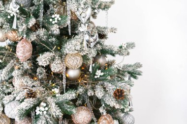 Süslü dallarla süslenmiş Noel ağacı, parıldayan süsler ve beyaz arka planda izole edilmiş parlak ışıklar. Bayram kutlamaları için şenlikli bir ortam. Duvar kağıdı, kopyalama alanı olan arkaplan