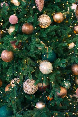 Altın ve bronz süslemelerle süslenmiş Noel ağacı ve parıldayan ışıklar çelengi. Şenlik dekorasyonu arka planı, duvar kağıdı, fon. Tatil atmosferi için şenlikli ev dekorasyonu.