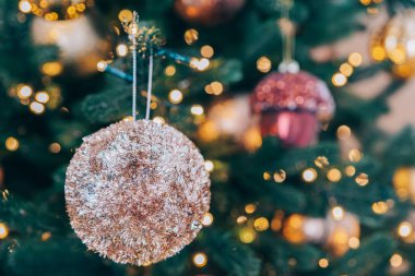 Noel ağacı çeşitli renklerde parlak süsler ve arka planda parlayan ışıklar barındırır. Dekorasyonlar sıcak ve neşeli bir ortam yaratıyor. Tatil mevsimi için mükemmel..