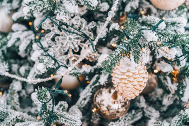 Karlı dalları olan Noel ağacı gümüş ve ışıklarla süslenmiş altın süsler. Kış tatili ve kutlamalar için mükemmel bir ortam. Duvar kağıdı, arkaplan, arkaplan