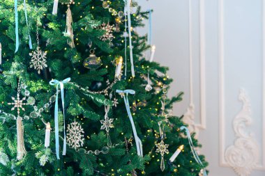 Güzel dekore edilmiş Noel ağacı dalları cam süslemeler ve beyaz alçı duvarda yanıp sönen ışıklarla süslenmiş kurdeleler. Tatil atmosferi için şenlikli ev dekorasyonu