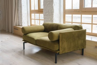 Sıcak yeşil haki rengi kadife kanepe. Parlak ve havadar bir yaşam alanı. Büyük pencereleri ve beyaz tuğlalı duvarları var. Modern tavan arası minimalist tasarımı. İç mekan, yaşam alanı, ev dekorasyonu.