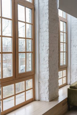 Çatı katında ahşap çerçeveli büyük pencereler modern apartman veya evin içinde beyaz tuğlalı duvarlar var. İç detay, mimari unsur, şehir tasarımı