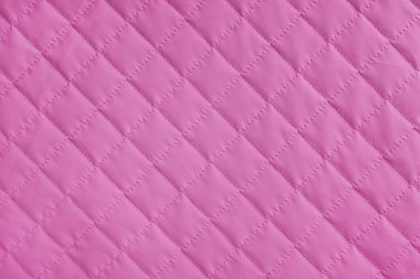 Damalı, elmas dikişli, pembe örtülü kumaş arkaplan. Battaniye ya da kabarık ceket, dikiş eşkenar dokusu yakın, makro. Duvar kağıdı, arkaplan.