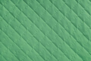 Damalı, elmas dikişli, yeşil örtülü kumaş arka plan. Battaniye ya da kabarık ceket, dikiş eşkenar dokusu yakın, makro. Duvar kağıdı, arkaplan.