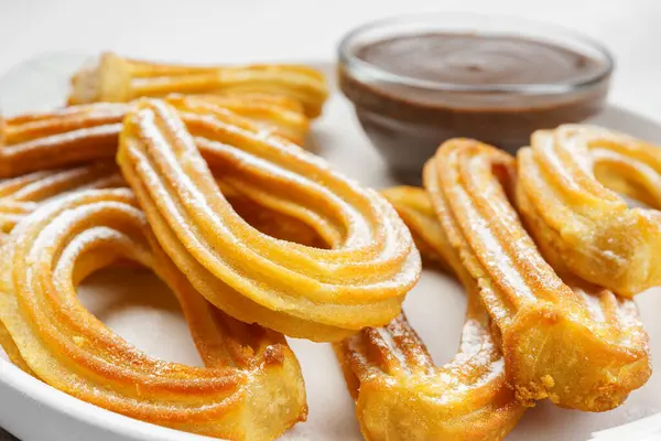 Geleneksel İspanyol tatlı churros, toz şeker ve çikolatalı sosis tozlu hamur tatlısı, yakın plan, beyaz arka plan. Sokak yemeği, tatlı atıştırmalık, ev yapımı tatlı.