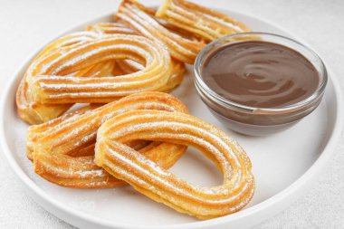 Geleneksel İspanyol tatlı churros, toz şeker ve çikolatalı sosis tozlu hamur tatlısı, yakın plan, beyaz arka plan. Sokak yemeği, tatlı atıştırmalık, ev yapımı tatlı.