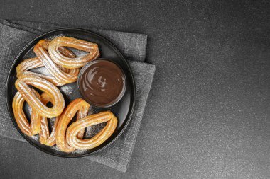 Geleneksel İspanyol tatlıları, pudra şekerli hamur tatlısı ve siyah arka planda çikolata sosu. Sokak yemeği, tatlı atıştırmalık, ev yapımı tatlı. Üst görünüm, alanı kopyala