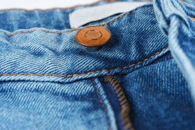Metal bakır düğme ve fermuarı gösteren kot pantolonun makro fotoğrafı. Görünür kumaş dokusu ve dikişler. Moda, giysi ve tekstil endüstrisi için harika..