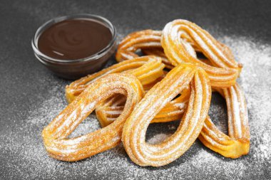 Geleneksel İspanyol tatlıları, pudra şekerli hamur tatlısı ve siyah arka planda çikolata sosu. Sokak yemeği, tatlı atıştırmalık, ev yapımı tatlı..