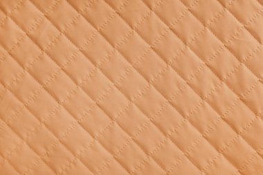 Damalı, elmas dikişli, turuncu örtülü kumaş arka plan. Battaniye ya da kabarık ceket, dikiş eşkenar dokusu yakın, makro. Duvar kağıdı, arkaplan.