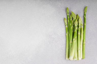 Açık gri desenli arka planda taze taze kuşkonmaz sapları. Üst görünüm, boşluğu kopyala. Sağlıklı gıda, taze ürün, yemek malzemesi, vejetaryen yemek tarifi, veya organik tarım, tarım.
