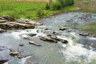 Hızlı akan bir dağ şelalesinin dinamik görüntüsü, yosunlu kayaların üzerine düşen hızlı bir nehir. Doğal suyun enerjisi ve güzelliği el değmemiş orman ortamlarında. Soyut doğal arkaplan