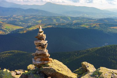 Carpathian dağının tepesindeki düz kayalardan yapılmış, arka plandaki uzak vadilerle dikkatlice dengelenmiş cairn. Seyahat ve yürüyüş keşfi sembolü, sakinlik, sessizlik ve denge
