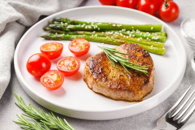 Yakından bakınca, yeşil kuşkonmaz ve beyaz tabakta, çatal bıçakla servis edilmiş vişneli domatesle servis edilen lezzetli biftek makrosu. Yemek menüsü, diyet ya da mutfak tasarımı için mükemmel..