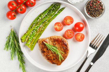 Yakından bakınca, yeşil kuşkonmaz ve beyaz tabakta, çatal bıçakla servis edilmiş vişneli domatesle servis edilen lezzetli biftek makrosu. Yemek menüsü, diyet ya da mutfak tasarımı için mükemmel..