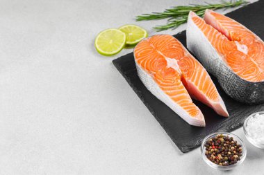 İki taze çiğ somon ya da besin maddeleri içeren beyaz taş yüzeyde alabalık bifteği. Limon, biberiye, tuz ve biber. Sağlıklı beslenme, deniz ürünleri, yemek pişirme, tarif ve menü kavramları. Üst görünüm, alanı kopyala