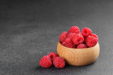 Yaklaş, kırmızı olgun ahududu makrosu kırsal ahşap kasede koyu dokulu arka planda fotokopi uzayı ile. Doğal, organik meyve sağlıklı yaşam tarzı ve temiz yeme temaları için hala hayat