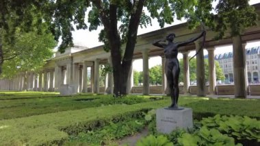 Berlin 'in merkezindeki Müze Adası' nda bir bahçenin alt perspektifi. Ön planda bir heykel ve arka planda uzun bir verandanın kemerleri. kaydırma kamerası taşı