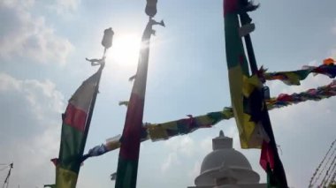 Direkte asılı olan Tibet dua bayrağı ön planda dalgalanıyor. Bir Budist tapınağının arka planında.